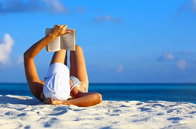 Woman reading a book on Daytona Beach tanning near the condo rental
